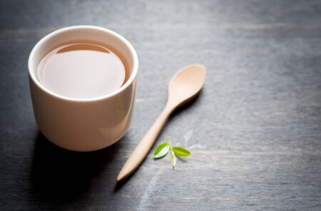 Cup of tea and tea leaves on dark woodenの写真素材