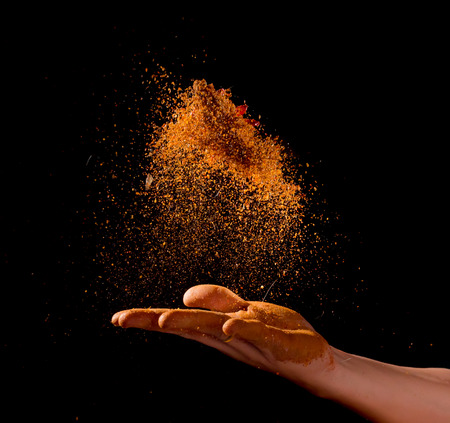 Cayenne pepper powder explosion with hand isolated on black background,Flying Cayenne pepper,Motion blurの写真素材