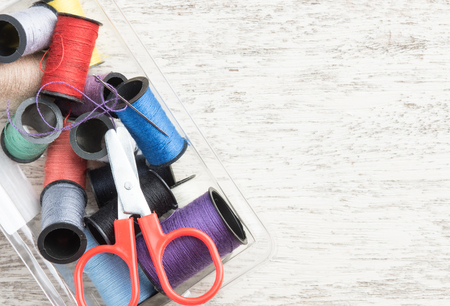 Sewing accessories,spools of thread with scissors on wood background,top view