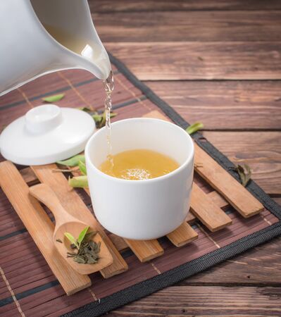 green tea pouring into tea cup on wooden backgroud.の写真素材