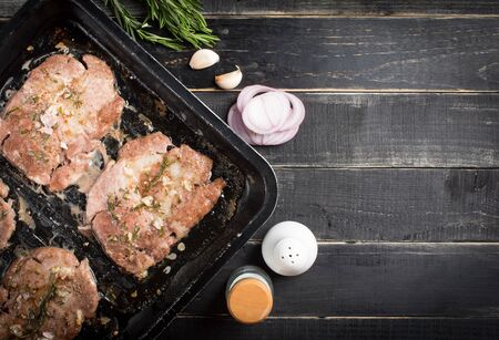 Raw fresh meat steak with rosemary leaves and salt on a black tray ready to be cooked, top viewの写真素材