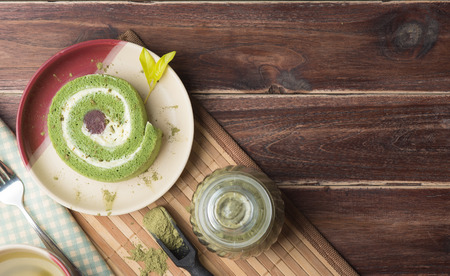 Green tea cake roll and hot green tea matcha on wood background,top view