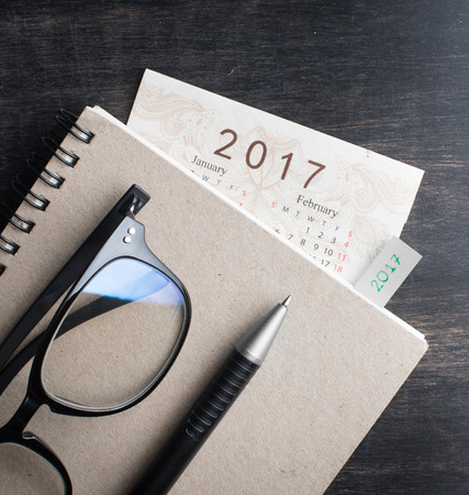 Daily note book with New Year 2017 office organizer calendar on wood tableの写真素材
