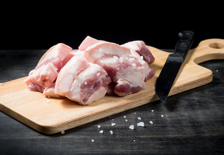 Pork belly on a wooden board over black background.の写真素材