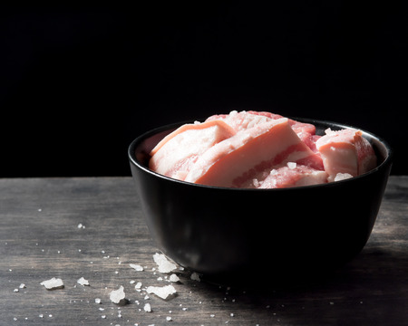 Pork belly in bowl over black background.の写真素材