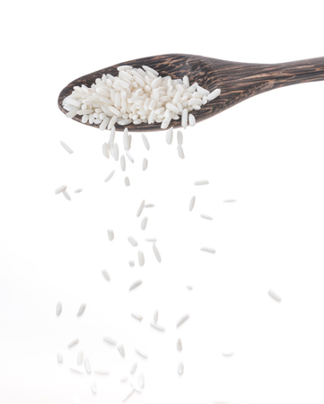 dropped rice grain down from a spoon isolated on white background.の写真素材