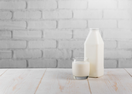 Fresh milk on wooden table against white brick wallの写真素材