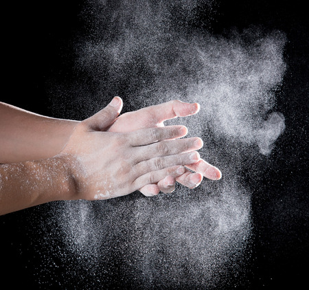 Chef hand clap with splash of white flour and black backgroundの写真素材