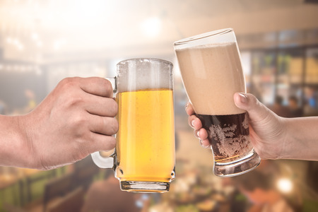 leisure and drinks concept , male hands clinking beer mugs at bar or pubの写真素材