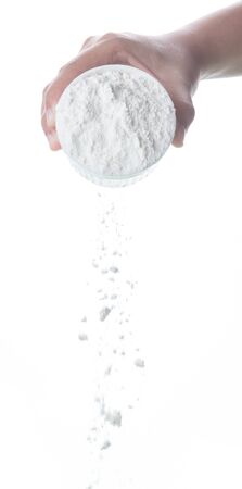 Pouring flour from the measure bowl on white backgroundの写真素材