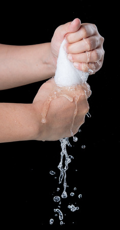 Hand squeeze wet fabric over dark backgroundの写真素材
