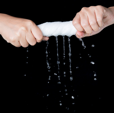 Hand squeeze wet fabric over dark backgroundの写真素材