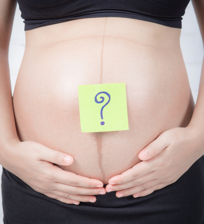 young pregnant woman with a sticker paper and a question on it ,boy or girl concept