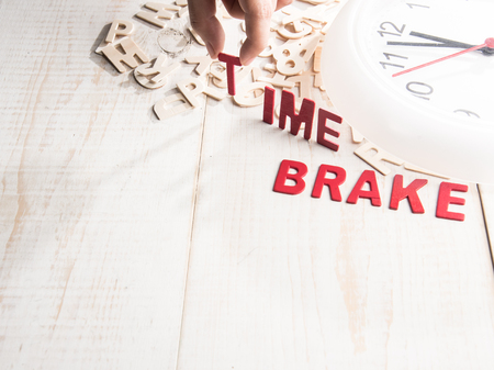 Wall clock and wording " TIME BREAK " on wooden with with Text Space,human's finger at T letter.の写真素材