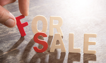 FOR SALE word made from wooden letters on wood with human's fingerの写真素材