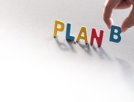 PLAN B word made from colored wooden letters with human's finger