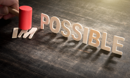 Hammer destroying the wooden letters in from the word impossible so it says possible.の写真素材