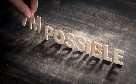 hand taking of the wooden letters in from the word impossible so it says possible.