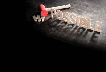 Hammer destroying the wooden letters in from the word impossible so it says possible.の写真素材