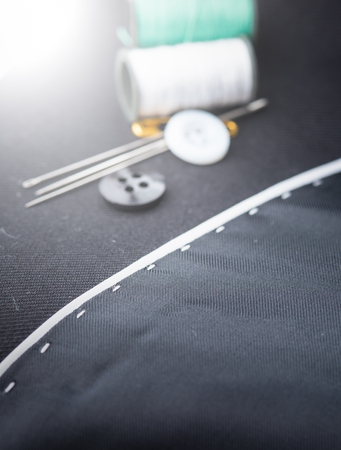 needles, cotton reels and buttons on black fabricの写真素材