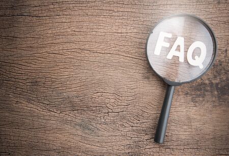 Magnifying glass on wood letters as FAQ abbreviation, frequently asked questions on wooden background.の写真素材