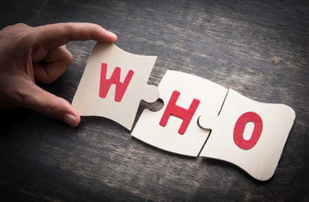 Hand holding wooden jigsaw puzzles with the word "WHO" on a rustic wooden,Jigsaw business idea conceptの写真素材