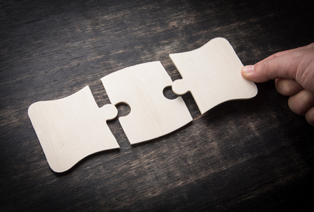 Hand holding jigsaw puzzles on a rustic wooden,wooden puzzle.の写真素材