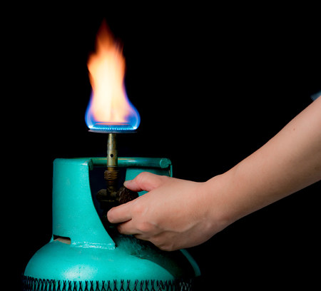 Male hand turning gas stove on a black background,operating valve of gas cylinder