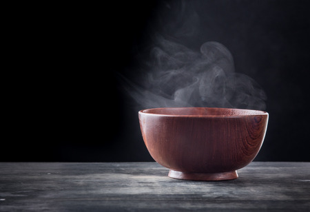 Steam of hot soup in a soup bowl with smoke on black backgroundの写真素材