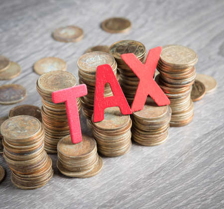 TAX wood word with stacked coins on wooden backgroundの写真素材