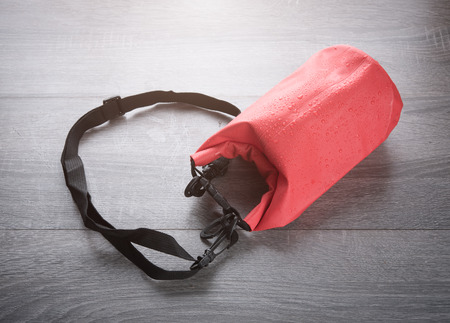 Red waterproof bag for protect your belonging from water on wood tableの写真素材