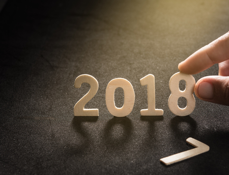 2018, Happy New Year,word of 2018 with human's finger at 8 letter on a black slate