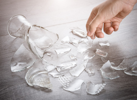 Picking broken bottle glass on wooden floorの写真素材