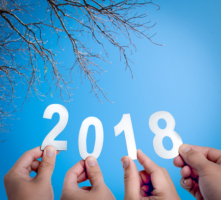 Happy new year concept of 2018,Hands holding Metal words of 2018 on a blue skyの写真素材