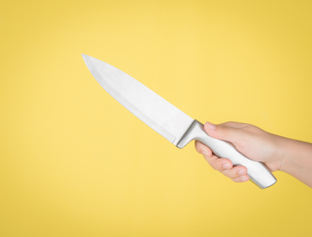 Knife in hand on yellow backgroundの写真素材