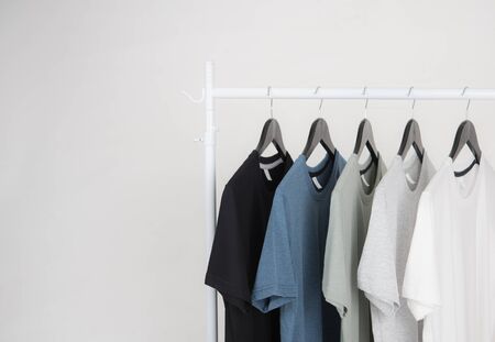 Black,blue, grey and white t-shirts on hangers on gray backgroundの写真素材