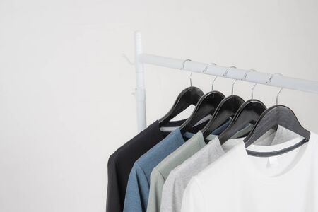 Black,blue, grey and white t-shirts on hangers on gray backgroundの写真素材