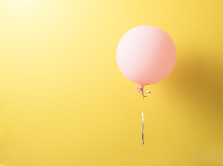 Pink balloon with shadows over yellow backgroundの写真素材