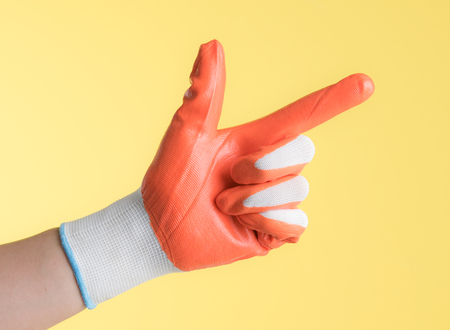 Hand with work glove against yellow backgroundの写真素材