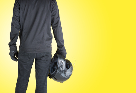 Biker with holding motorcycle helmet on yellow background,Text Spaceの写真素材