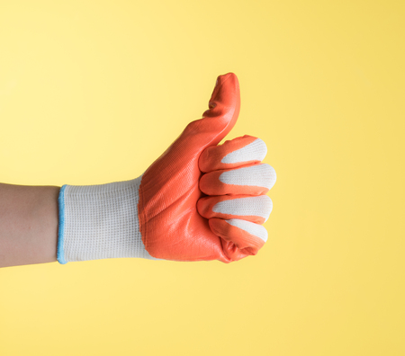 Hand with work glove against yellow backgroundの写真素材