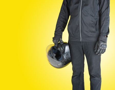 Biker with holding motorcycle helmet on yellow background,Text Spaceの写真素材