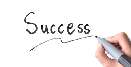 Hand holding black permanent marker and writing word "Success"on white backgroundの写真素材
