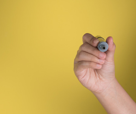 Hand holding a black marker with text space against yellow backgroundの写真素材