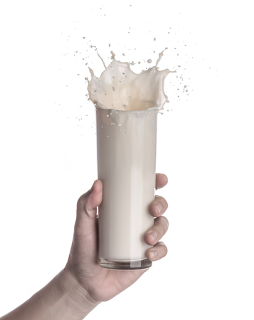 Hand holding glass of milk with a splash isolated on a white backgroundの写真素材