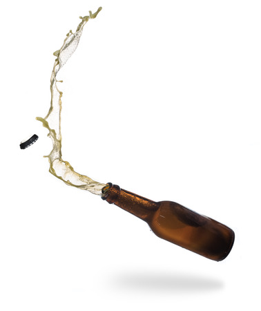 Gold beer bottle opening with exploding and splashing isolated on white backgroundの写真素材