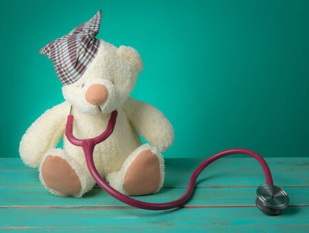 Teddy bear using a stethoscope on wood,Blue backgroundの写真素材