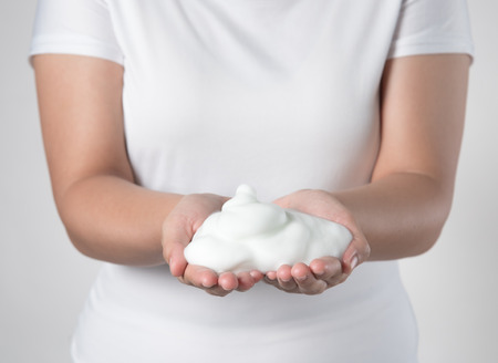 Shave foam (cream) on woman's hands,against gray background