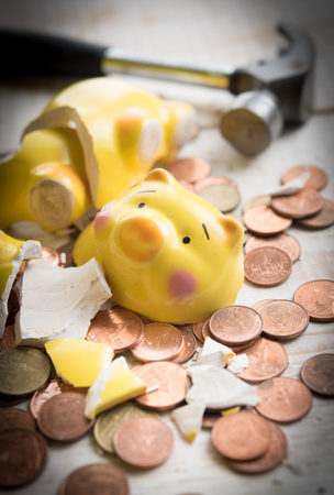 Broken piggy bank with cash and coins on woodenの写真素材