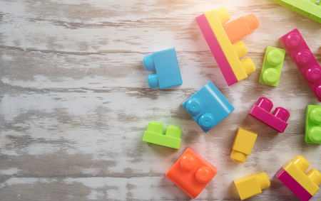Colorful toy bricks on a white wooden background